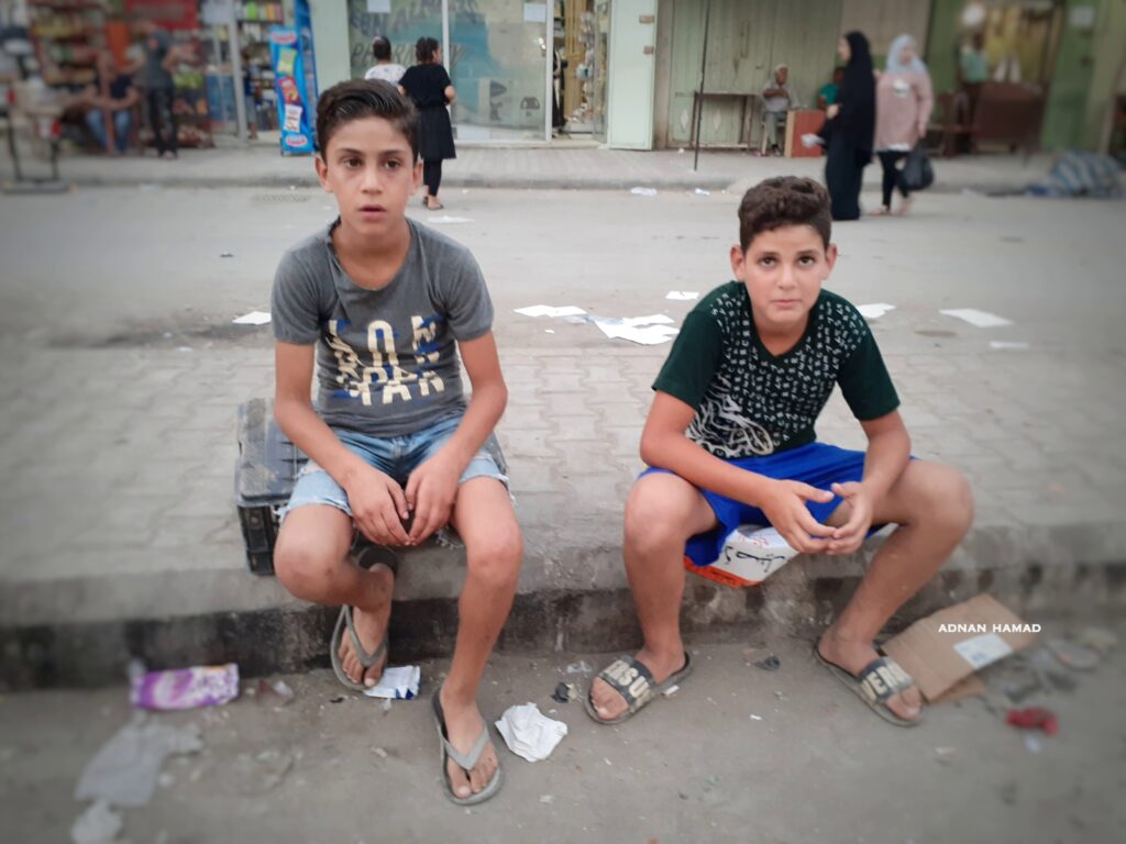 أطفال في مخيم نهر البارد للاجئين الفلسطينيين يجلسون على حافة الطريق بالقرب من سوق الخضار في المخيم (بعدسة عدنان الحمد)