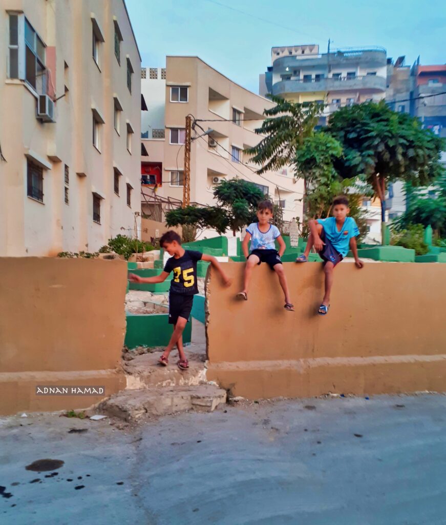 أطفال يلعبون بالقرب من المقبرة أمام جامع فلسطين في مخيم نهر البارد للاجئين الفلسطينيين في طرابلس، شمال لبنان (بعدسة عدنان الحمد)