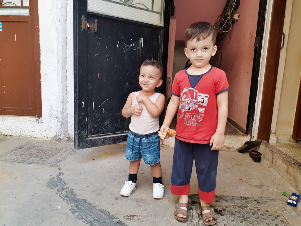 طفلان أمام منزلهما في أحد أزقة مخيم نهر البارد للاجئين الفلسطينيين يبتسمان لعدسة مصور موقع شبابيك في البارد عدنان الحمد