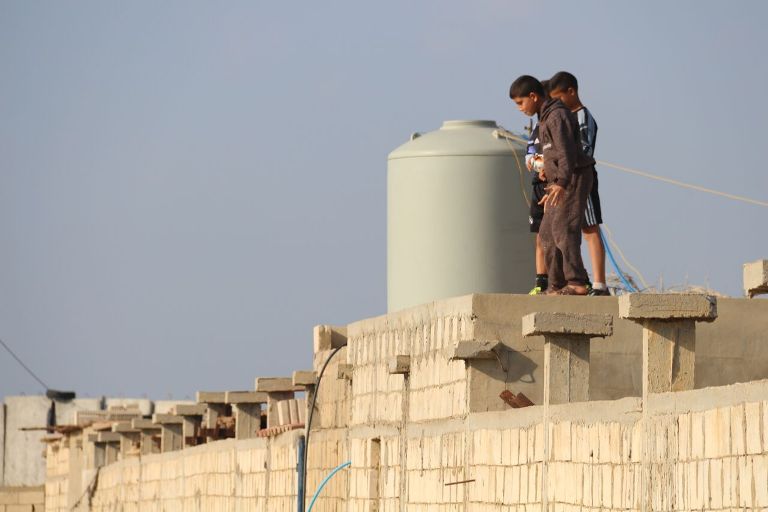 أطفال يقفون بجانب خزان المياه على سطح أحد المباني في مخيم الرشيدية جنوب لبنان (بعدسة رانية سعد الله)