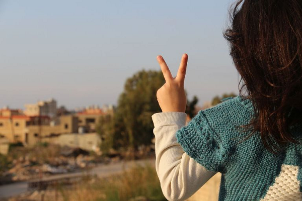 طفلة من مخيم الرشيدية في منطقة صور جنوب لبنان ترفع علامة النصر (بعدسة رانية سعد الله)