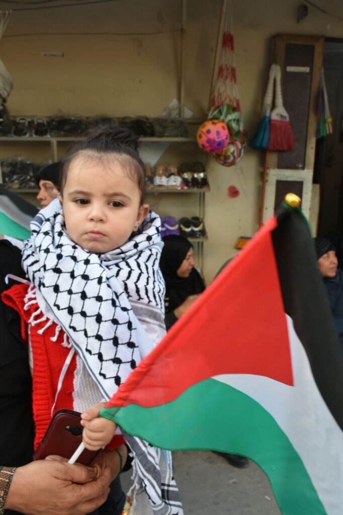 طفلة تحمل علم فلسطين خلال مشاركتها في اعتصام ليوم الأرض في مخيم برج الشمالي (محمد فيصل محمود)