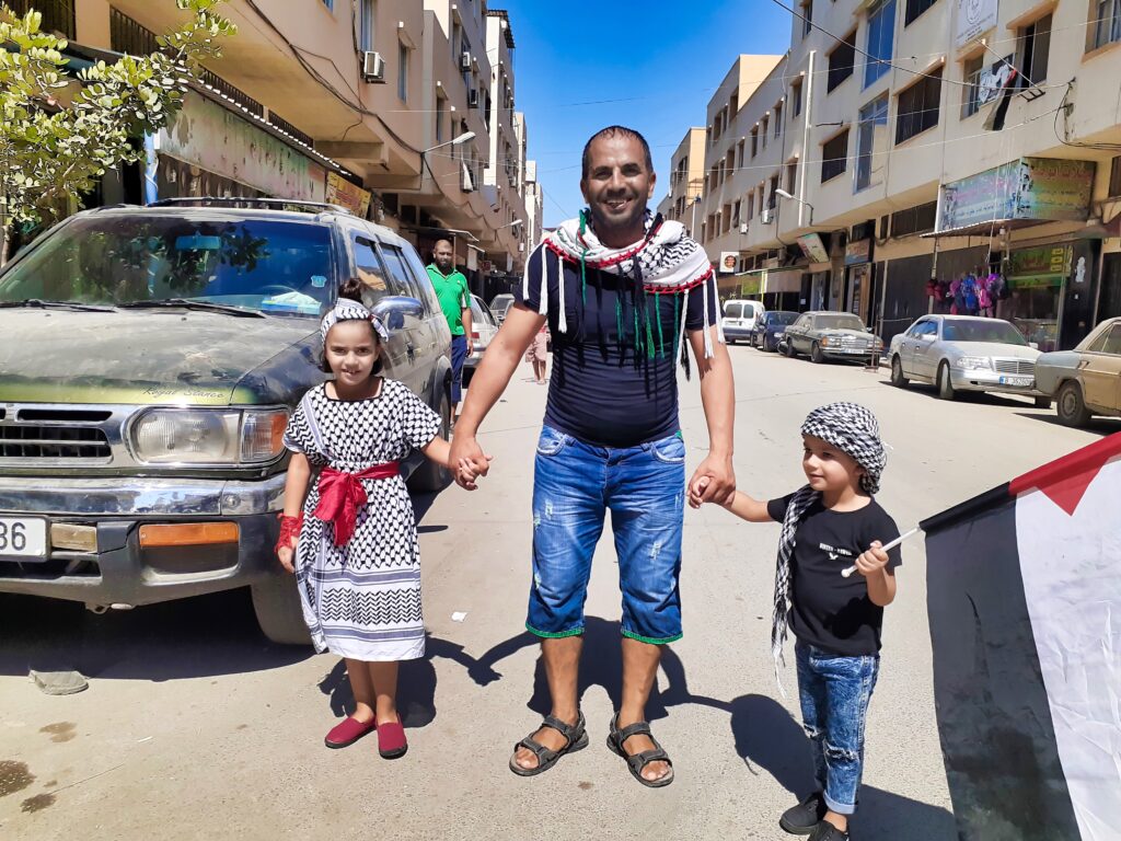 أب وطفليه مشاركون في أحد الإعتصامات ضد إجراءات وزارة العمل اللبنانية بحق العمال الفلسطينيين في مخيم نهر البارد للاجئين الفلسطينيين، طرابلس، شمال لبنان (بعدسة عدنان الحمد)