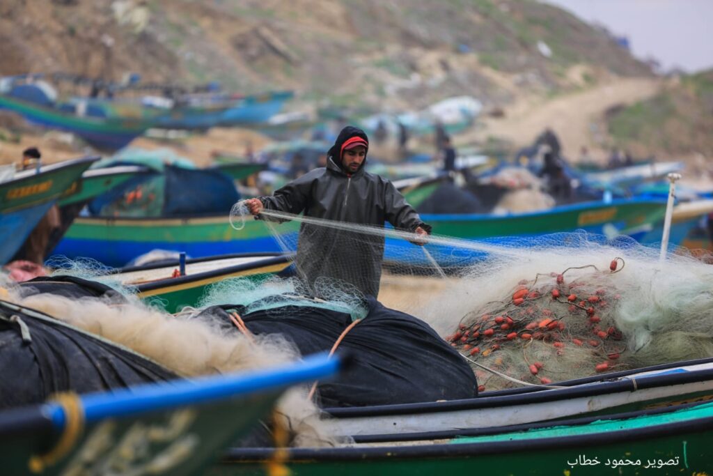 صياد على شاطىء دير البلح يقوم بجمع شبكة الصيد الخاصة به بعد رحلة صيد في بحر غزة (بعدسة محمود خطاب)