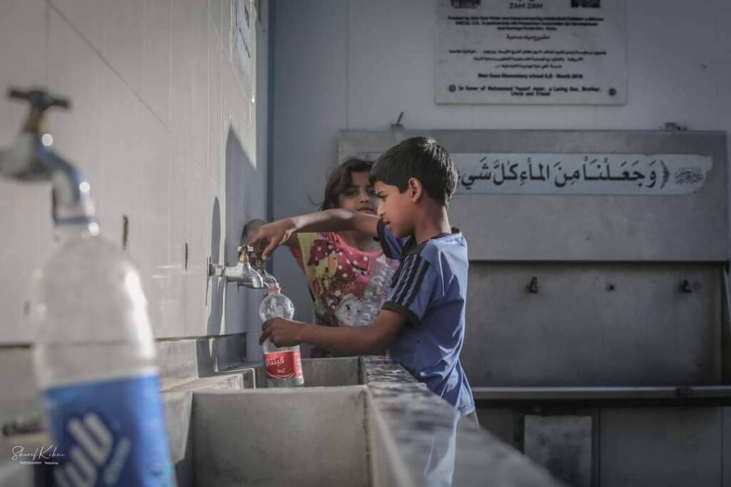 طفل في أحد مراكز الايواء يقوم بتغبئة الماء أثناء العدوان الاسرائيلي على غزة (بعدسة شرف كيلاني)