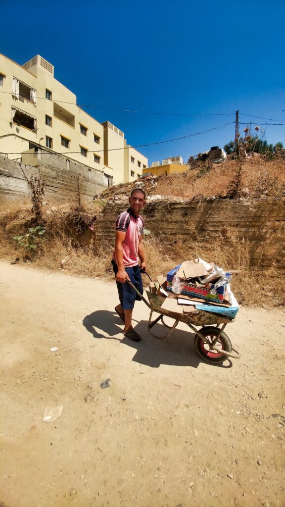 عمر شاب من مخيم نهر البارد يجمع النفايات في المخيم ويرميها في الأماكن المخصصة لها من أجل لقمة العيش (بعدسة عدنان الحمد)