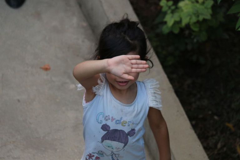 طفلة من مخيم الرشيدية في منطقة صور جنوب لبنان تُغطي عينيها بكفيّها للتهرب من التقاط صورة لها (بعدسة رانية سعد الله).