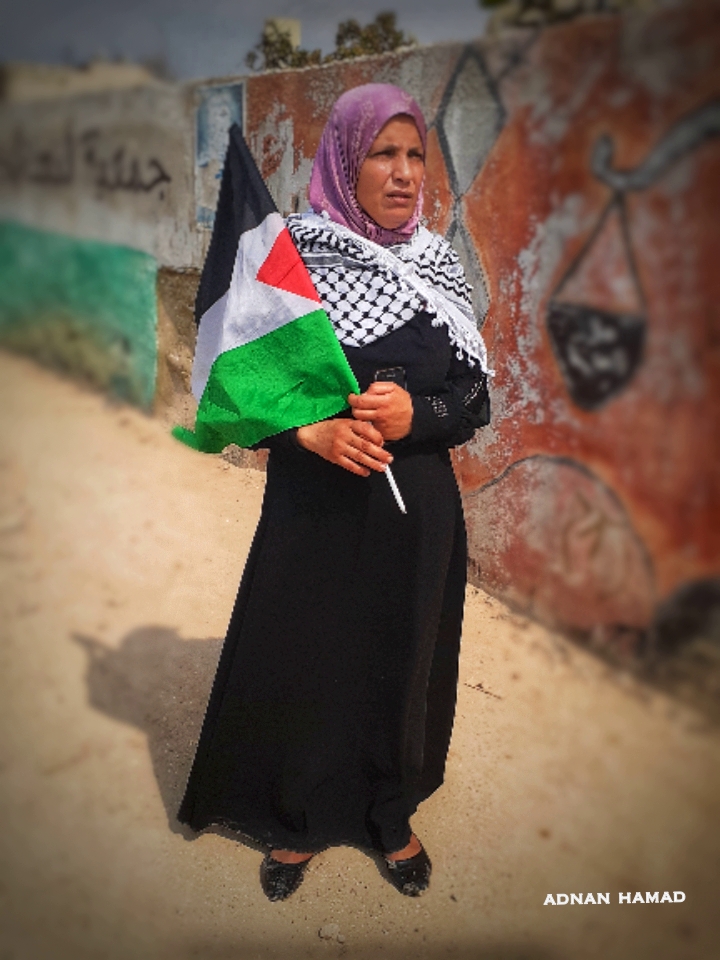 سيدة تحمل العلم الفلسطيني في مخيم نهر البارد للاجئين الفلسطينيين في مدينة طرابلس، شمال لبنان (بعدسة عدنان الحمد)